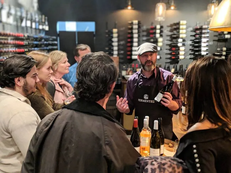 A Fermented staff member presenting a bottle to guests during a live tasting.